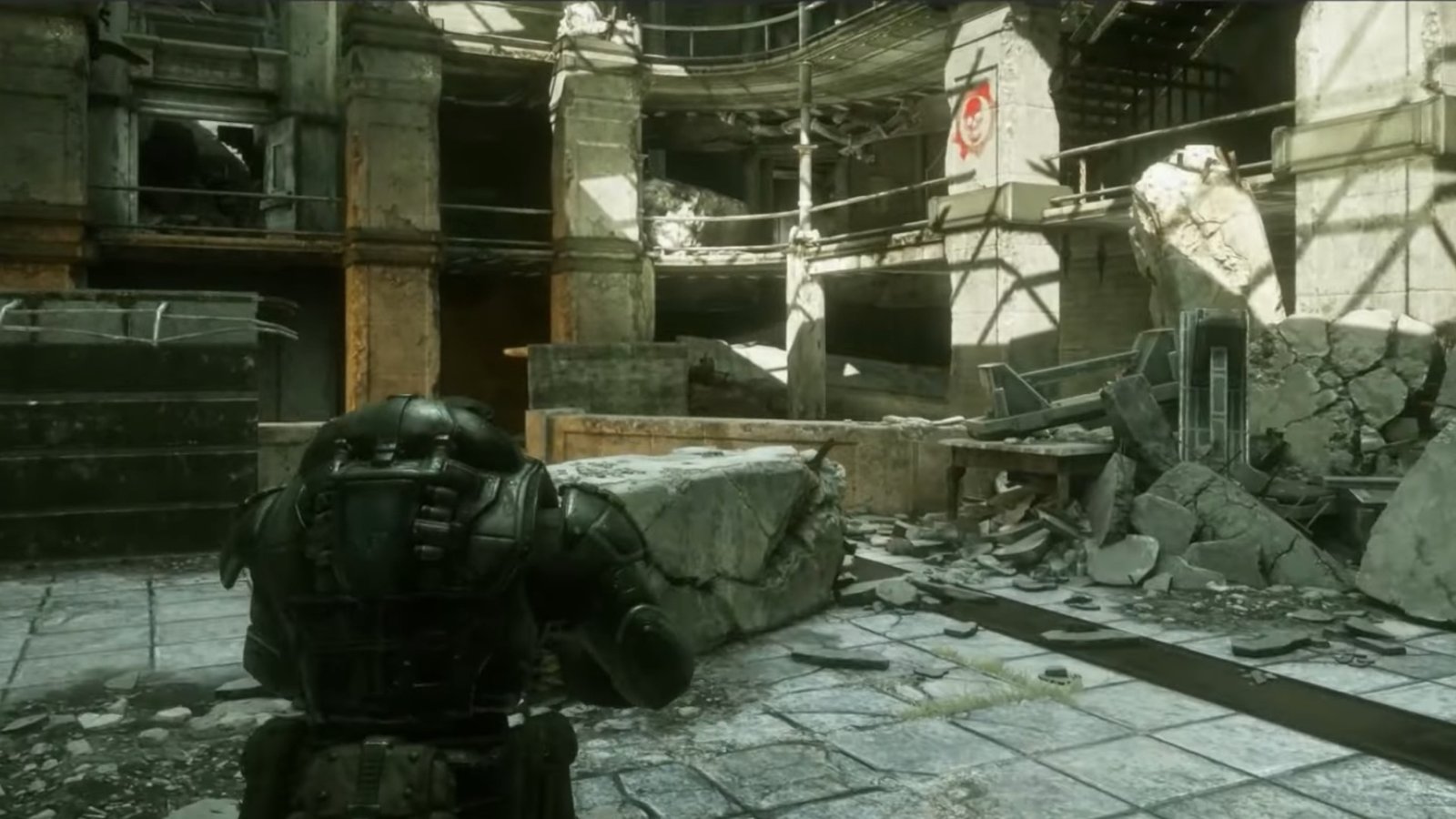 Gears of War: Reloaded screenshot featuring a pillar with the Gears of War icon and the COG Tag underneath the stairs beside it.